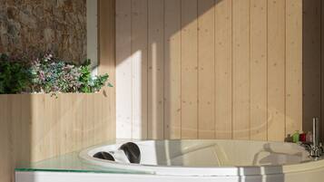 Relax in a spacious bathroom with a large hot tub and stone accent wall.