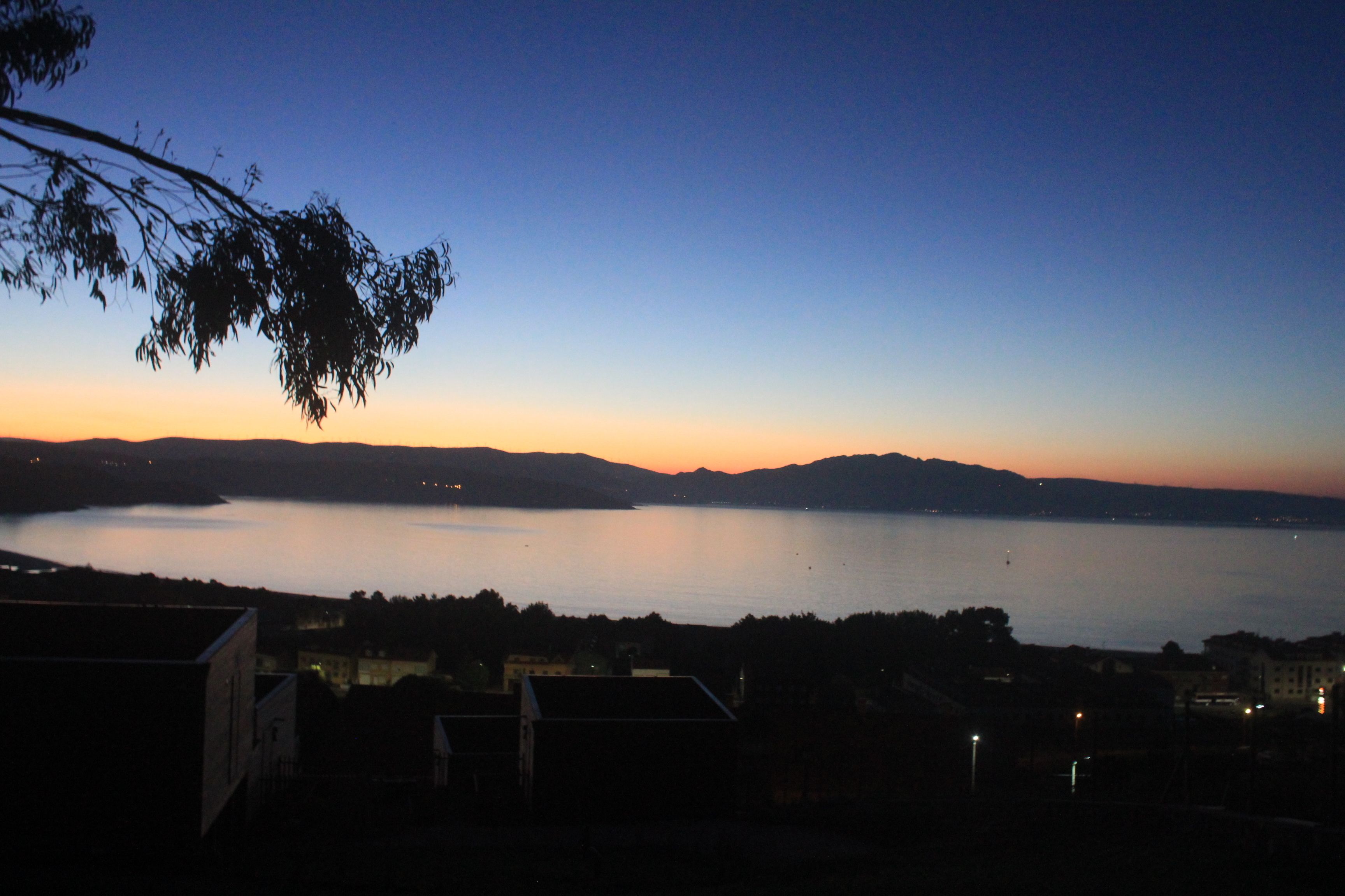 A lakeside view at dusk with buildings in the foreground.