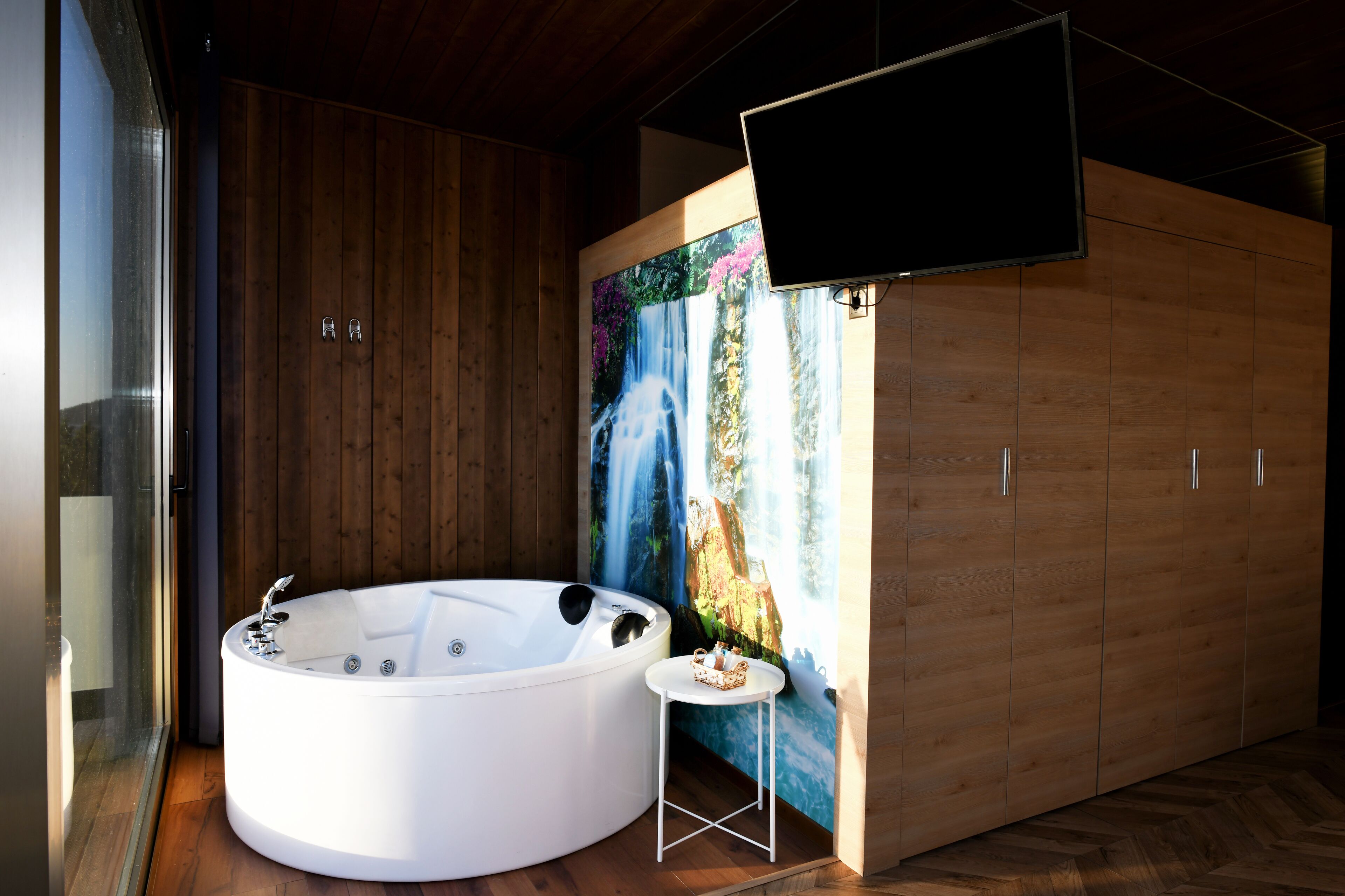 Une salle de bain moderne dotée d’un grand jacuzzi, de meubles en bois et d’une grande fresque murale.