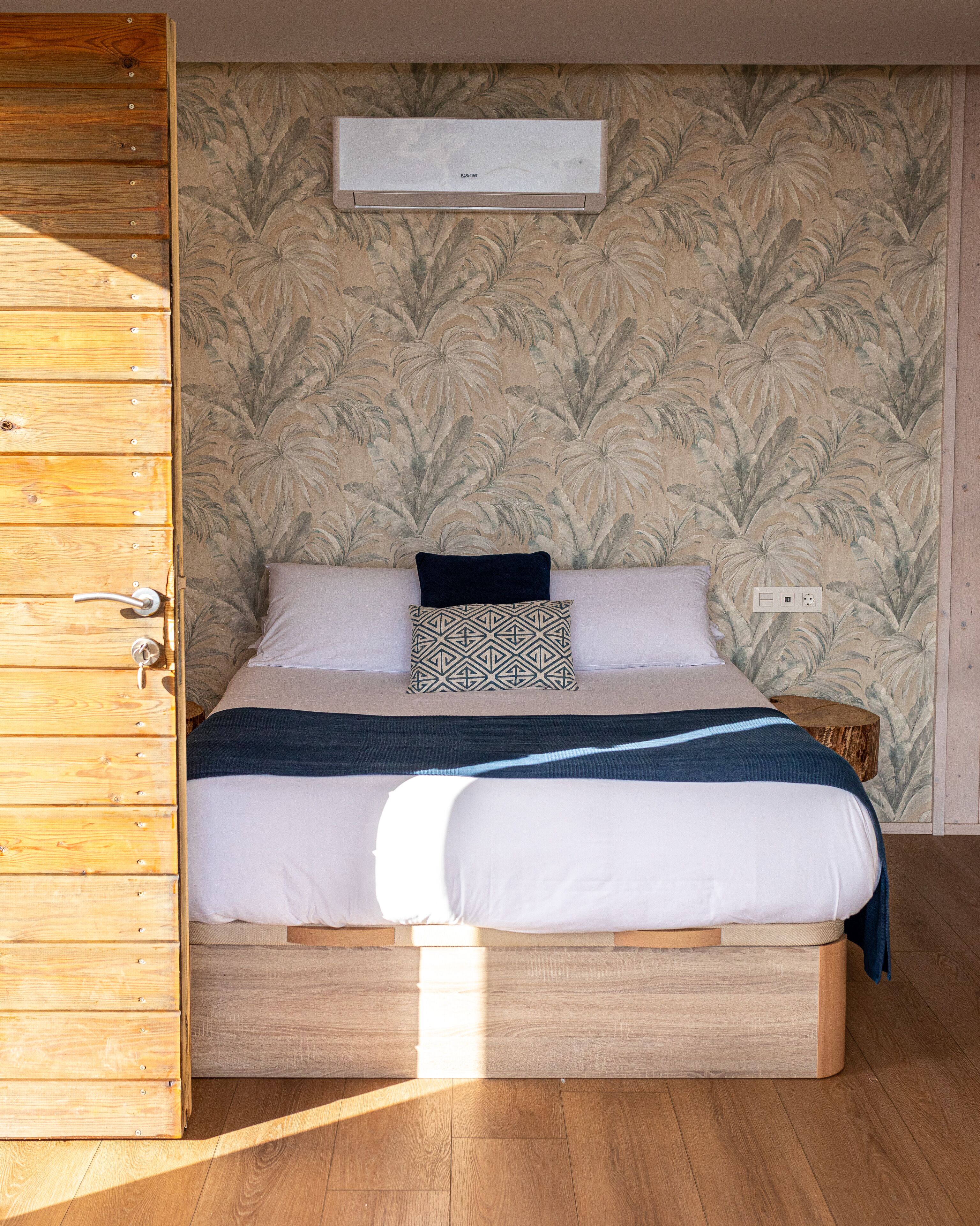 Une chambre à coucher avec un lit en bois, un mur à motifs et une armoire en bois.