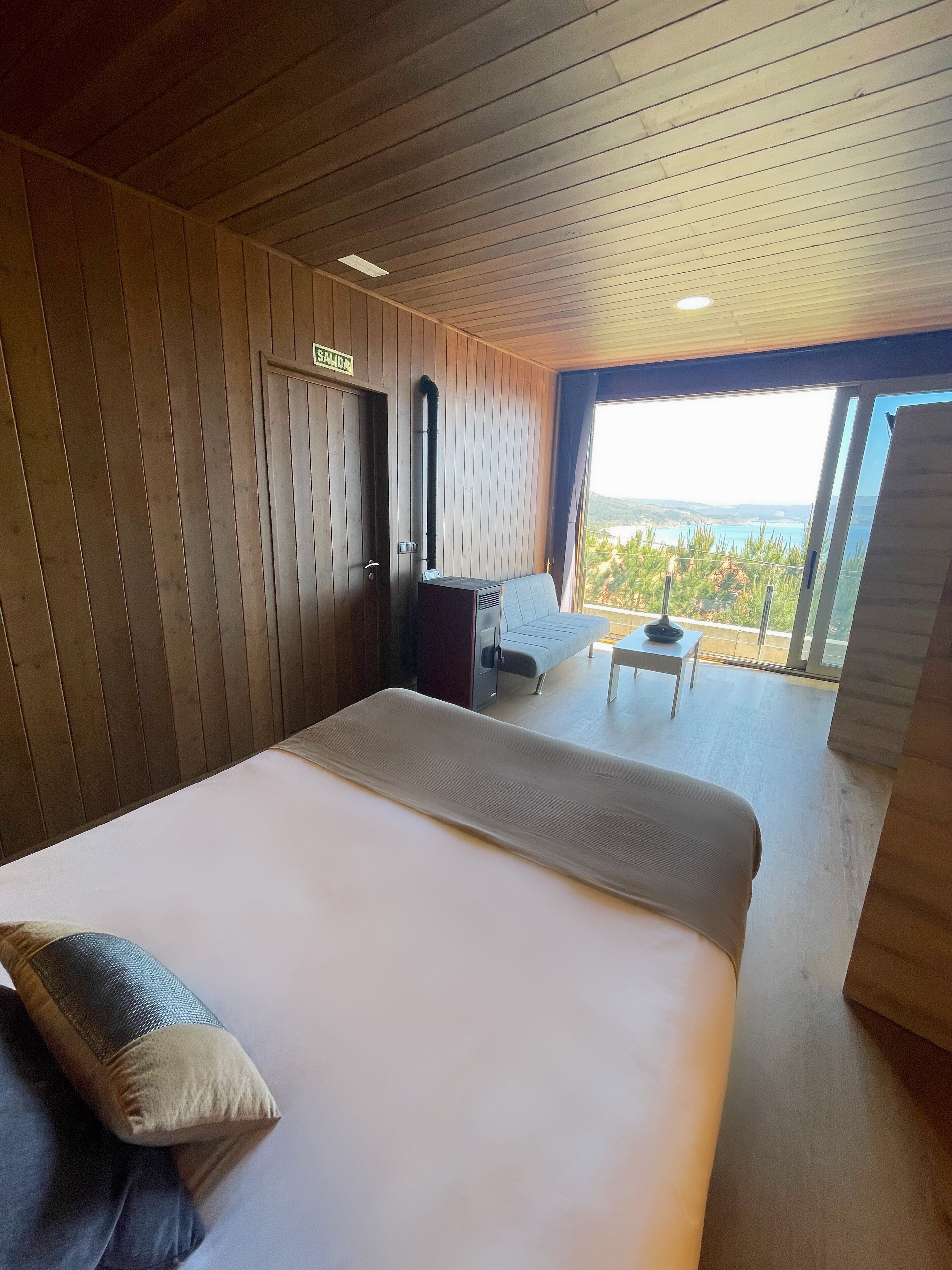 A bedroom with a large bed, a desk, and a view of the outdoors.