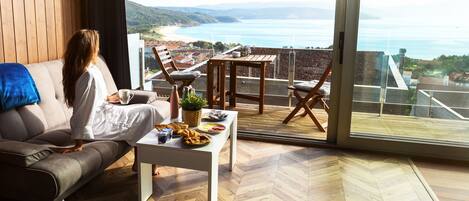 Un salón moderno con un ventanal que ofrece vistas panorámicas de la costa.
