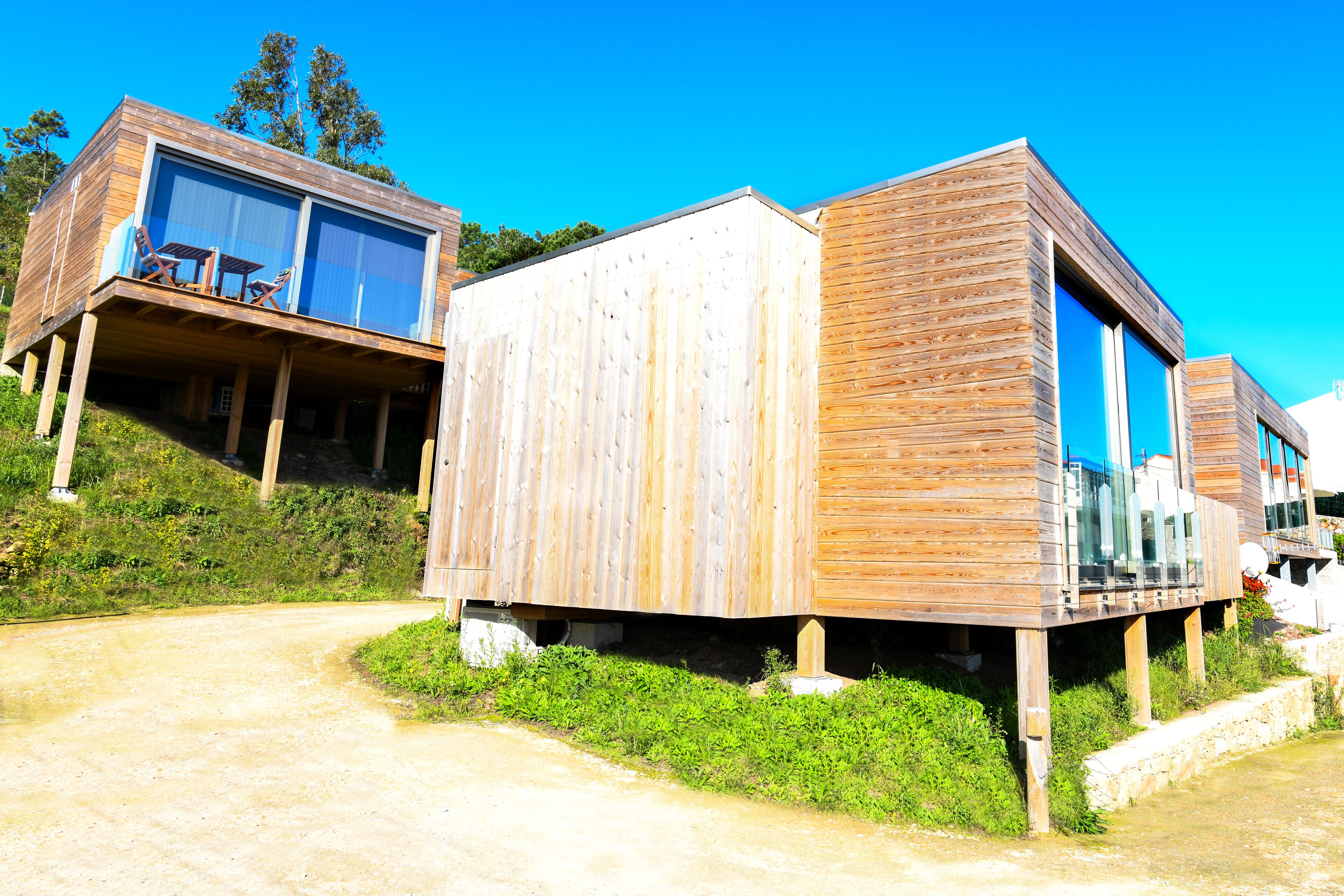Una cabaña moderna de madera con un porche y ventanas amplias.