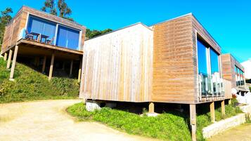 Una cabaña moderna de madera con un porche y ventanas amplias.