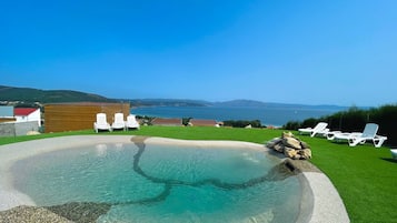 Una piscina al aire libre, sillones reclinables de piscina