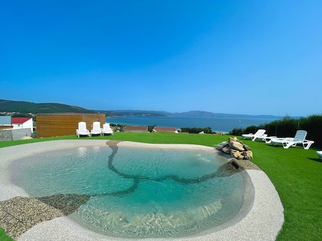 Una piscina al aire libre, sillones reclinables de piscina