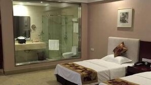 A hotel room with two beds, a large mirror, a shower, and a small bedside table. - Airport Hotel Hefei (Hefei)