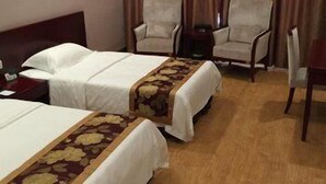 A hotel room with two beds, a wooden headboard, a small table, two armchairs, and a curtain. - Airport Hotel Hefei (Hefei)