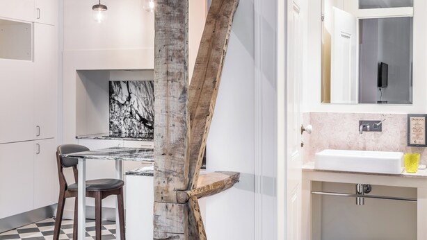 Eine moderne Küche mit Marmorfliesenspiegel, einer Holz-Akzentwand und einem Essbereich mit Glastisch und Stühlen.