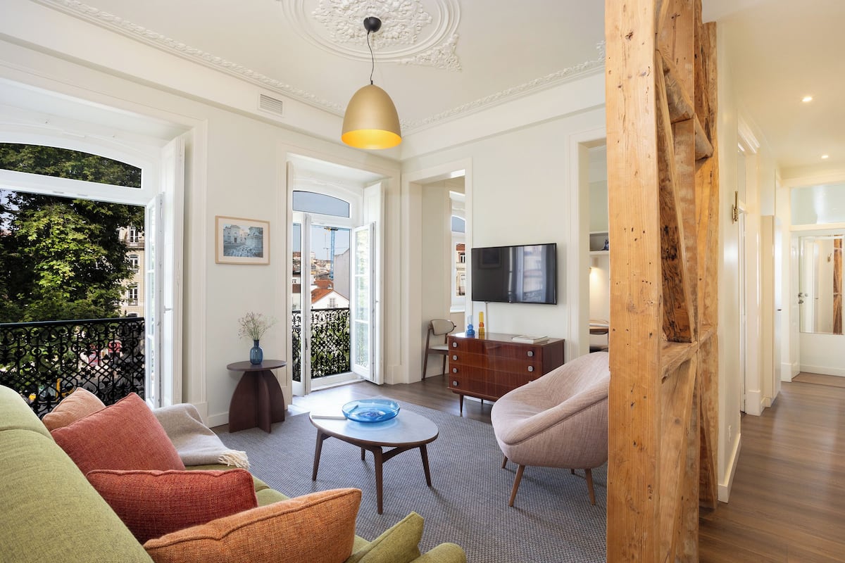 Un salon spacieux avec une grande fenêtre, une table basse ronde et un téléviseur.