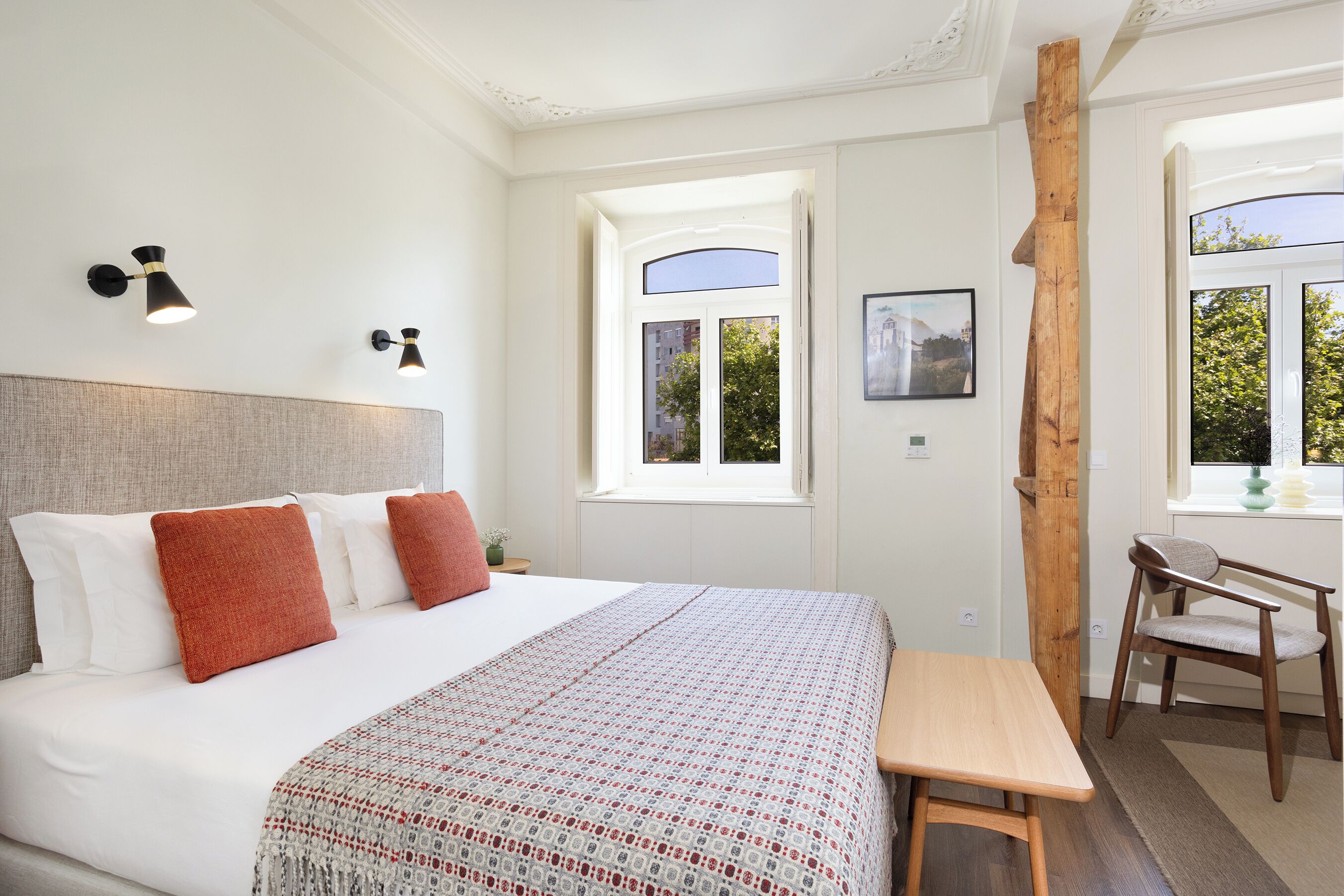 Een slaapkamer met een bed, nachtkastjes, een bureau en een raam met uitzicht.