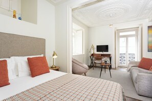 Een hotelkamer met een bed, een bureau, een televisie en een balkon.