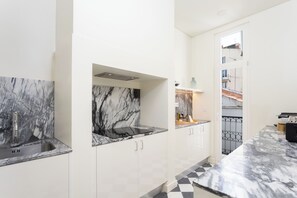 A kitchen with marble countertops, white cabinetry, and a black and white checkered floor. - Hermitage Castelo - Casa Chafariz (Lisbon)