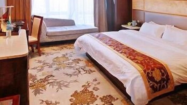 A hotel room with a large bed, a desk, a chair, and a window with curtains. - Jinxi International Hotel (Fuzhou)