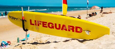 A lifeguard stand on a sandy beach with a clear blue sky.