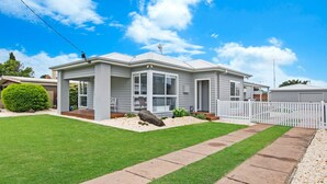 A single-story house with a covered porch, a fenced yard, and a well-maintained lawn. - Fielding's Lair - Pet Friendly (Port Fairy)