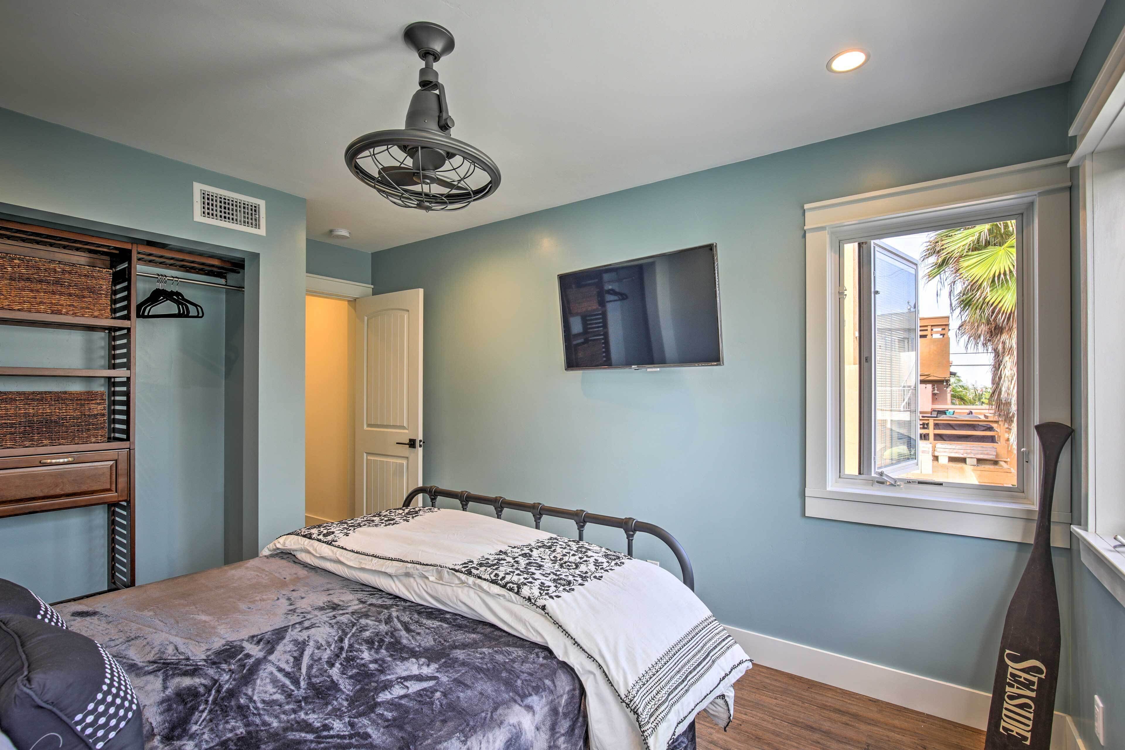 Une chambre à coucher comprenant un lit, une armoire, un ventilateur de plafond, une fenêtre et une vue sur l’extérieur.