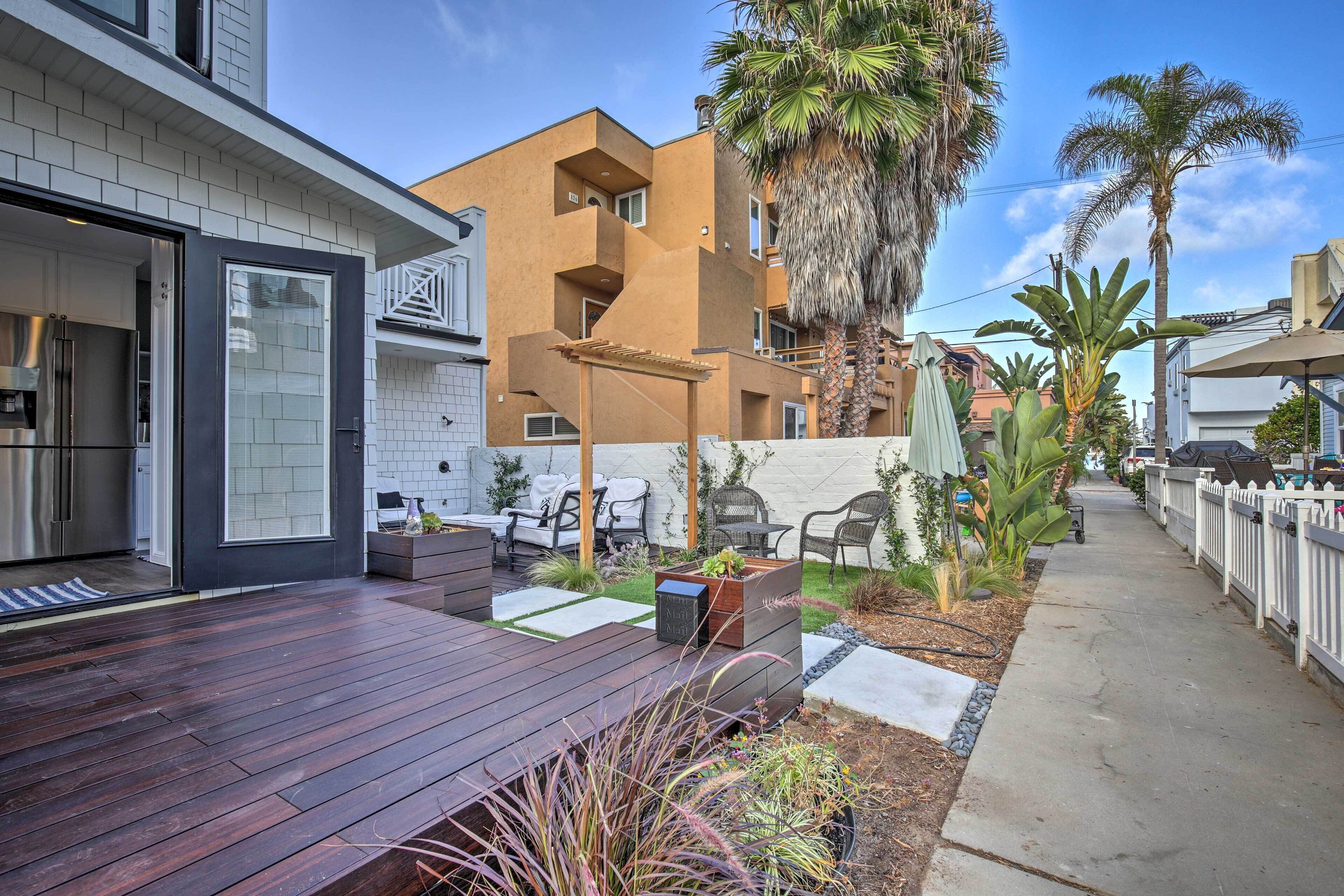 A modern residential area with a wooden deck, outdoor seating, and a variety of plants.