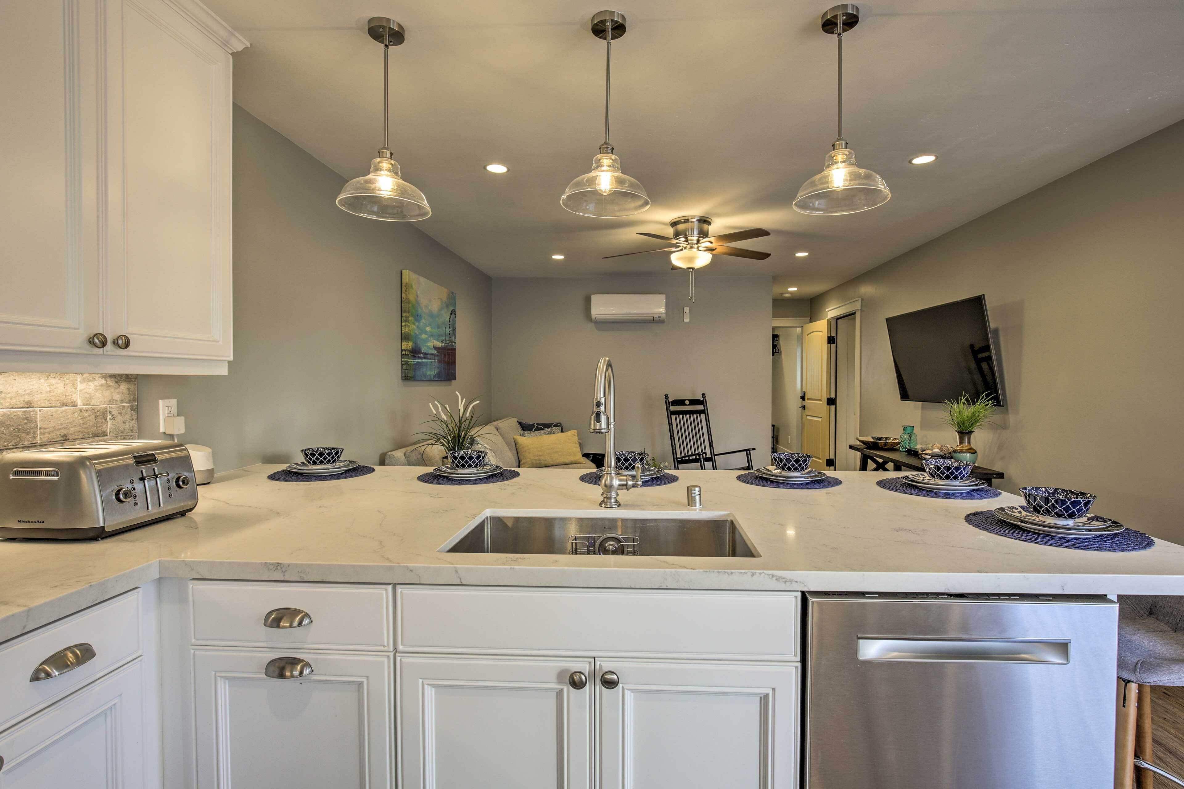 A modern kitchen with white cabinetry, a stainless steel refrigerator, and a central island with a sink.