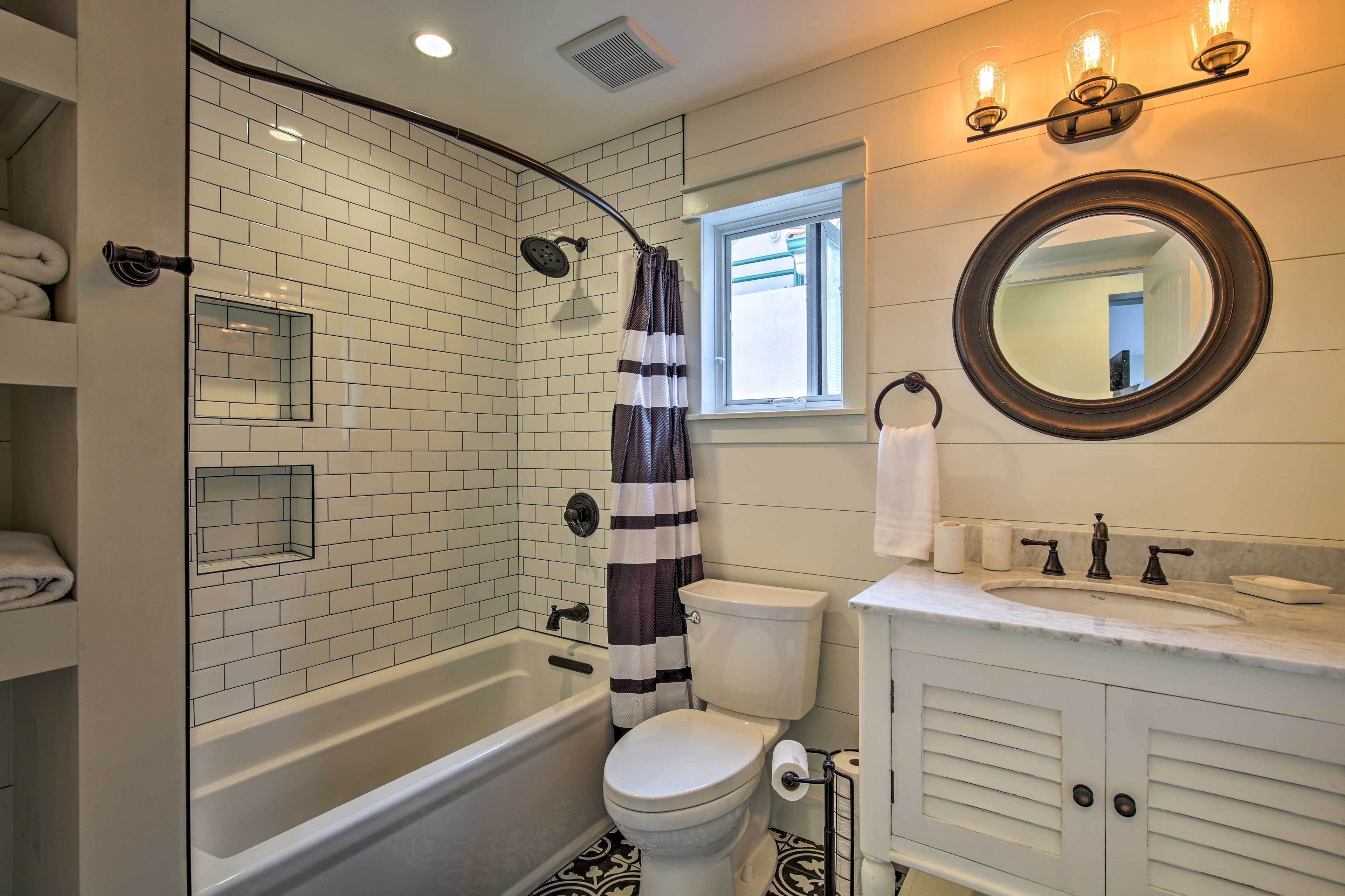 A bathroom with a white bathtub, a toilet, and a sink with a mirror above it.