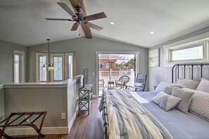 A bedroom with a bed, a ceiling fan, a desk, and a view of the outside balcony. - San Diego Home - Walk to Sail Bay & Mission Beach! (San Diego)