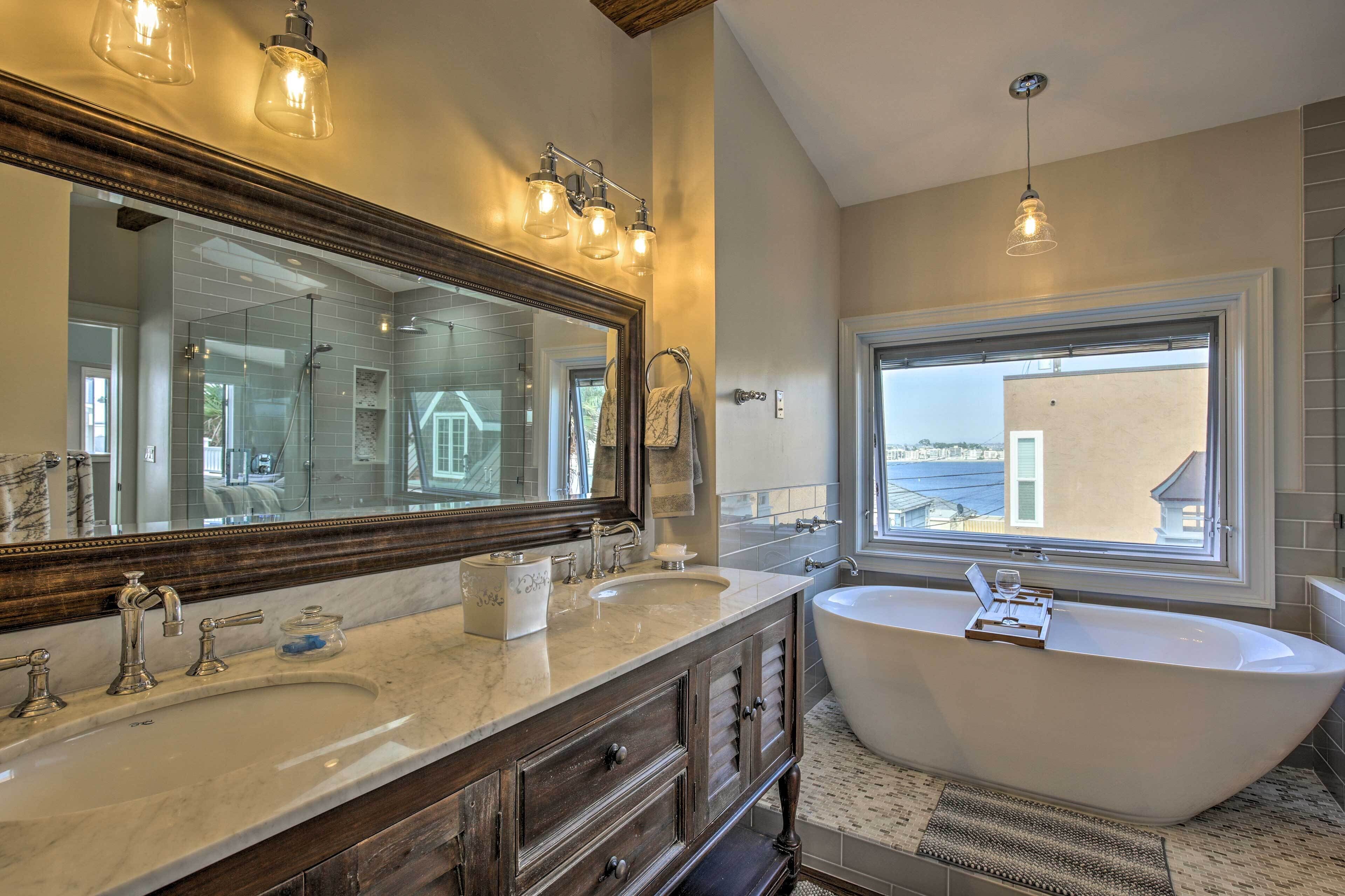 A bathroom with a large mirror, two sinks, a bathtub, and a window with a view.