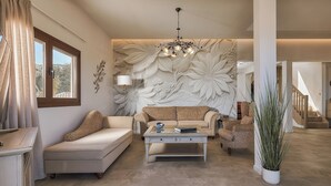 Una sala de estar con sofá, sillón, mesa de centro y una planta grande en maceta.