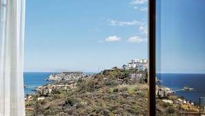 Vista costera con edificios en una ladera, cielo despejado y el mar.