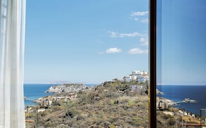 A coastal view with buildings on a hillside, a clear sky, and the sea.