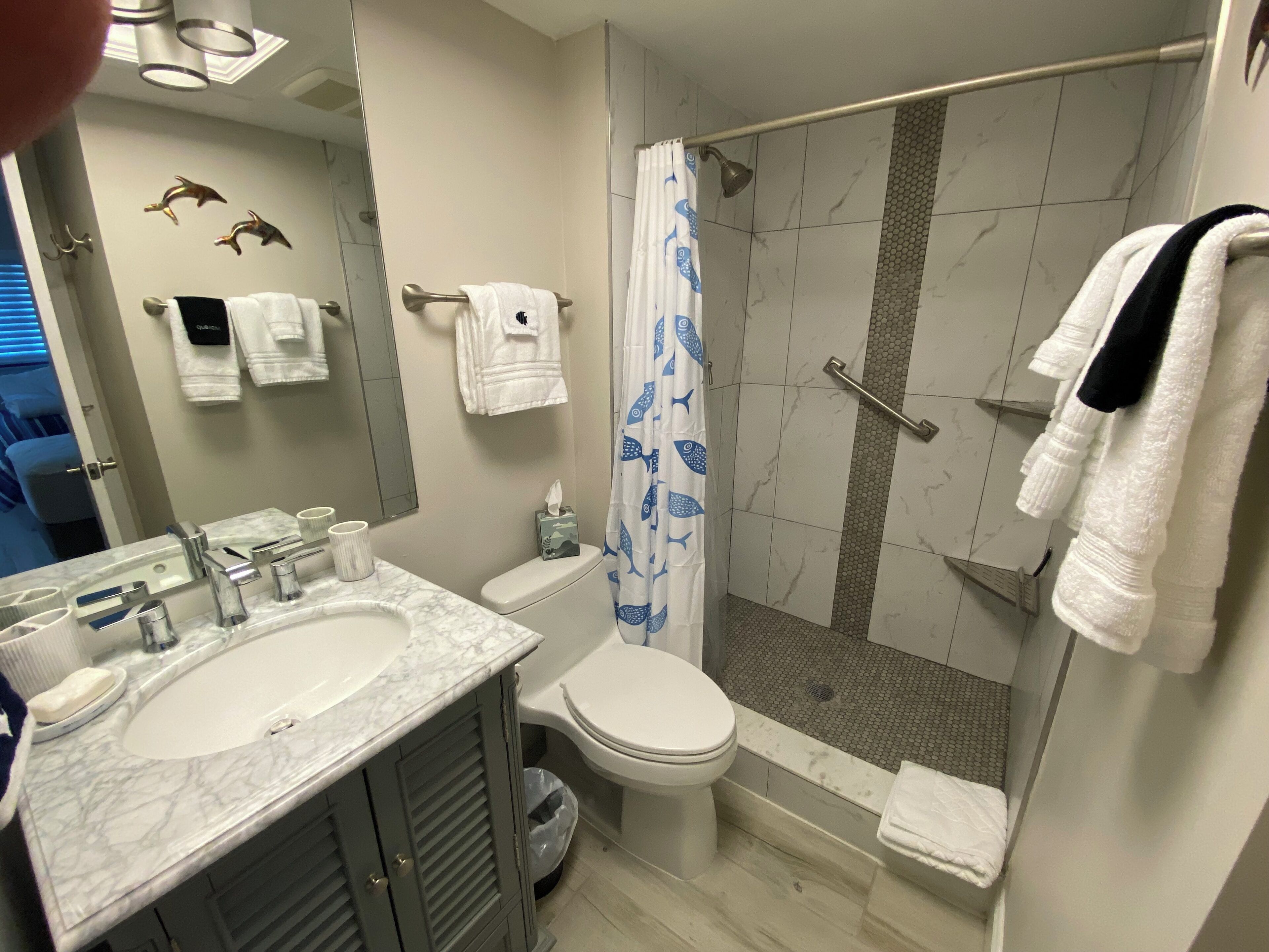 A bathroom with two sinks, a toilet, a shower with a glass door, and a towel rack.