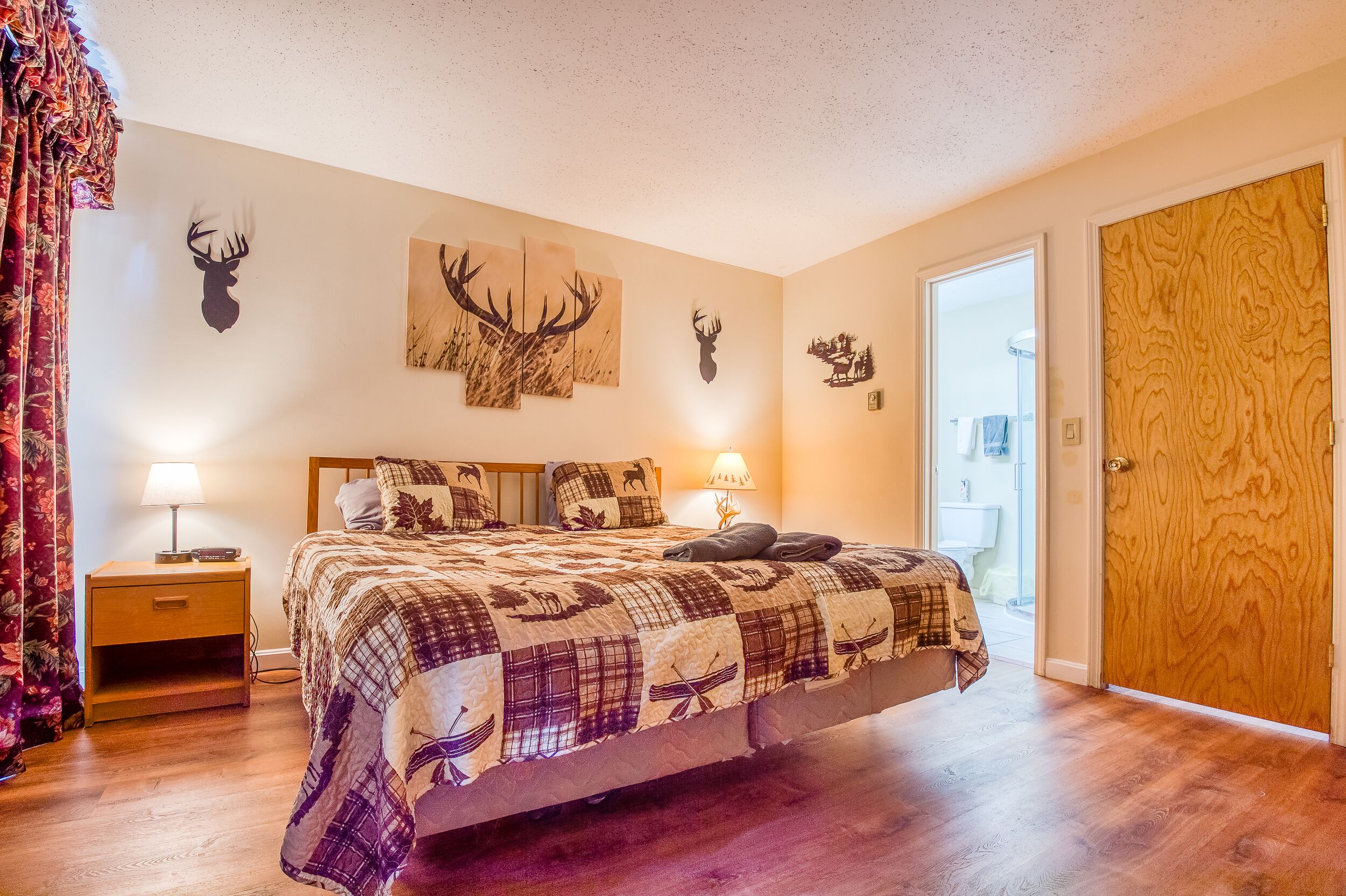 Une chambre avec un grand lit, deux lampes de chevet et des décorations murales sur le thème des cerfs.
