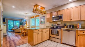 Una cocina amplia con armarios de madera, microondas, lavavajillas y un comedor con mesa y sillas de madera.