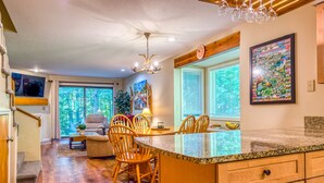 Una cocina amplia con encimera de granito, sillas de madera y una mesa de comedor.