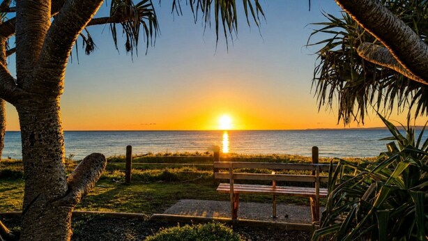 A sunset over a body of water with a bench in the foreground. - Walk to Suft Beach on Boyd (WOORIM)