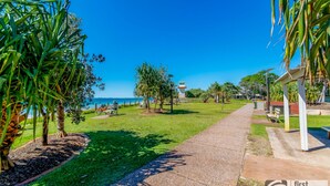 A pathway leading to a beach with palm trees and a lifeguard tower. - Walk to Suft Beach on Boyd (WOORIM)