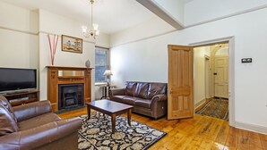 A living room with a fireplace, leather sofa, and a television. - Situated in the CBD district with easy access to all Warrnambool has to offer (Warrnambool)