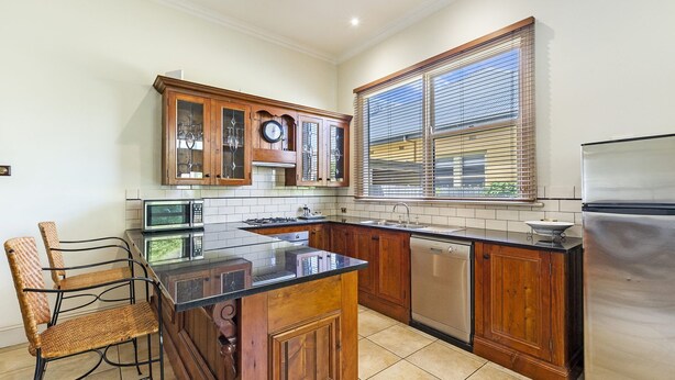 A kitchen with wooden cabinets, a built-in microwave, a dishwasher, and a refrigerator. - Situated in the CBD district with easy access to all Warrnambool has to offer (Warrnambool)