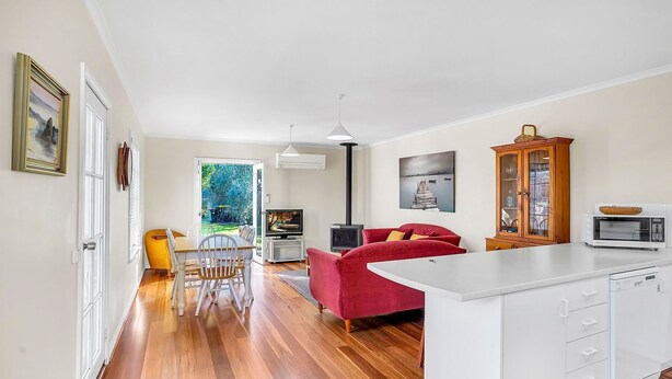 Une cuisine moderne avec un îlot central blanc, un canapé rouge et un coin repas comprenant une table et des chaises en bois.
