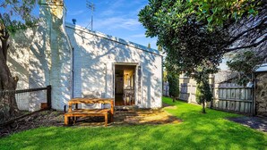 Un petit bâtiment rustique, avec un banc en bois devant, un ciel dégagé et une pelouse bien entretenue.