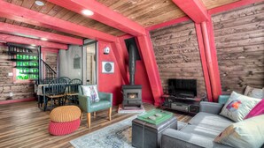 Una sala de estar acogedora con techo de madera, chimenea, sofá y comedor.