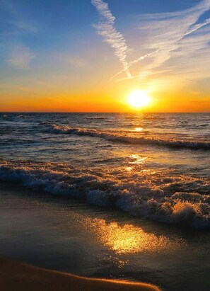 Un coucher de soleil sur l’océan, avec des vagues.