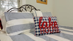 A bed with striped bedding and a pillow with "lake house" text. - B and B's Beach House Accommodates Eleven Guests In 5 Bedrooms 2 Full Baths! (South Haven)