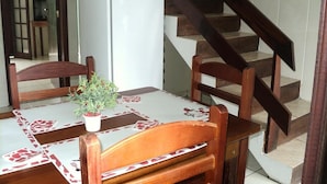 Een eethoek met een tafel, stoelen, een potplant en een koelkast.