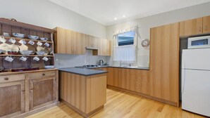 Eine Küche mit Holzausstattung, einem eingebauten Backofen und einem Fenster mit Vorhängen.