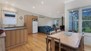 Eine moderne Küche mit Holzausstattung, einer integrierten Mikrowelle und einem Essbereich mit einem Holztisch und Stühlen.