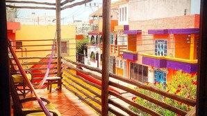 A balcony with a hammock, wooden chairs, and a tiled floor.