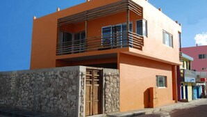 A two-story building with a stone wall foundation, a balcony with metal railings, and a wooden door.