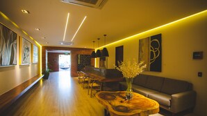 Eine moderne Hotelhalle mit einem Holzbüro, einer Couch und einem Blumenstrauß.