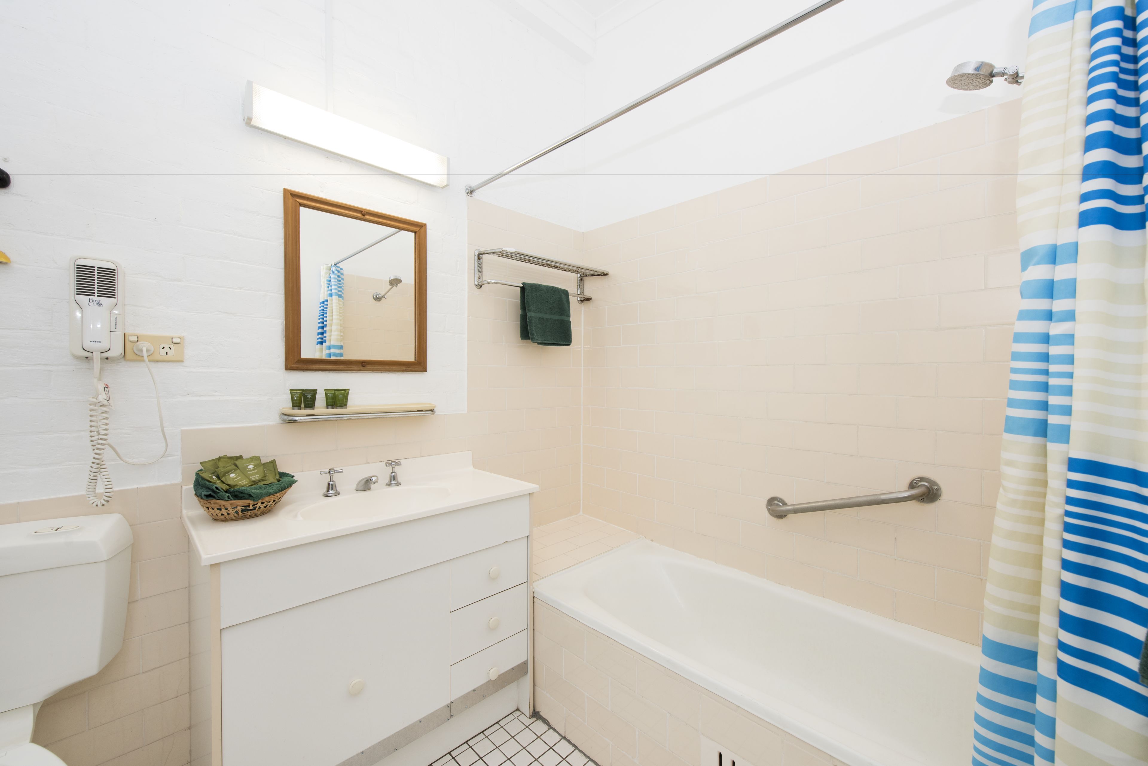 A bathroom with a bathtub, a toilet, a sink, a mirror, and a shower curtain.