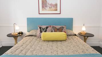 A neatly made bed with a patterned bedspread, two bedside tables with lamps, and a framed picture on the wall.